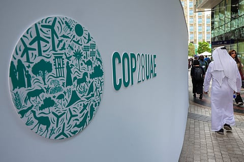 Participants walk past a COP28 sign at the Expo City during the United Nations climate summit in Dubai on December 3, 2023. (Photo by Giuseppe CACACE / AFP)