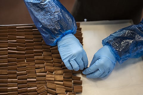 An employee prepares a tray of the famous chocolate treat shaped like lingots, the 'Gianduiotto' at Guido Castagna laboratory, on 12 December 2023 in Giaveno near Turin, Northwestern Italy. In Turin, a committee was formed made up of large and small local chocolate producers in order to obtain PGI recognition (Protected Geographical Indication) for one of the most famous products in the area: the gianduiotto. But the Swiss Lindt group, owner of the Caffarel brand, opposes it. (Photo by MARCO BERTORELLO / AFP)