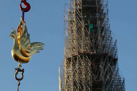 The new golden rooster containing relics is lifted by crane to be installed atop the spire of Notre Dame cathedral as part of its reconstruction, in central Paris on December 16, 2023. Photo by Thomas SAMSON / AFP