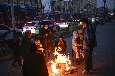 People gather next to a fire on a street after an earthquake in Dahejia, Jishishan County in northwest China's Gansu province on December 19, 2023. (Photo by Pedro Pardo / AFP)