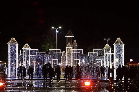 Syrians walk past Christmas decorations at a market in the capital Damascus on 23 December 2023. (Photo by LOUAI BESHARA / AFP)