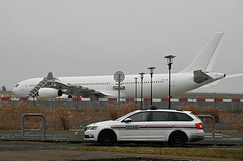 This photograph taken on December 25, 2023, shows a French customs car with an Airbus A340 in the background which was grounded on the tarmac since December 21 over suspected "human trafficking", at the Vatry airport, north-eastern France. Photo by FRANCOIS NASCIMBENI / AFP