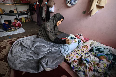 Iman al-Masri, a displaced Palestinian who fled from her home in Beit Hanoun with her family to escape Israeli bombardment, feeds one of her quadruplets - with the fourth still being treated in hospital - as they take shelter at a school in Deir al-Balah in the central Gaza Strip on December 27, 2023, amid continuing battles between Israel and the militant Hamas group. (Photo by Mahmud HAMS / AFP)