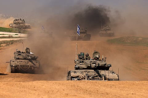 This photograph taken in Israel near the border with the Gaza Strip shows Israeli troops on tanks rolling back from the Gaza Strip, on 31 December 2023 amid continuing battles between Israel and the militant group Hamas. (Photo by Menahem KAHANA / AFP)