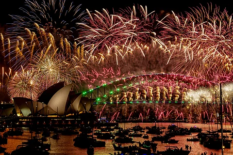 Fireworks explode over the Sydney Harbour Bridge and Sydney Opera House (L) during New Year's Eve celebrations in Sydney on January 1, 2024. (Photo by Izhar KHAN / AFP)