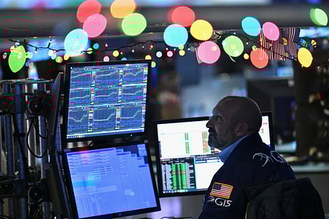 FILE PHOTO: Lighting bourse up Christmas lights lift up the spirit of a stock trader as investors recalibrated their outlook for the new year after the Federal Reserve indicated it would cut interest rates. (Photo by ANGELA WEISS/Agence France-Presse)