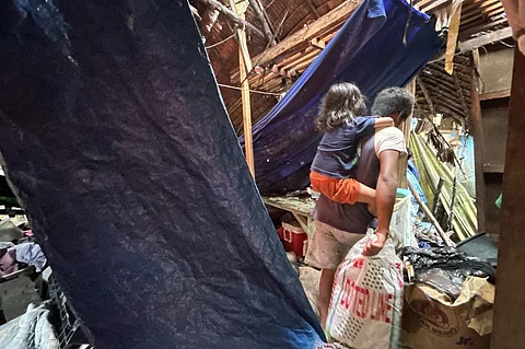 A man carries a child and belongings as they walk past a destroyed house in Hinatuan, Surigao del Sur province on 3 December 2023, following a 7.6 magnitude earthquake late on 2 December. (Photo by AFP)