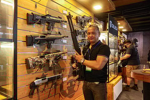 Photograph by DIANNE BACELONIA for the daily tribune
DAILY TRIBUNE’s associate editor John Henry Dodson displays a shotgun featured at the 29th AFAD Defense and Sporting Arms Show at the SMX Convention Center on Thursday.