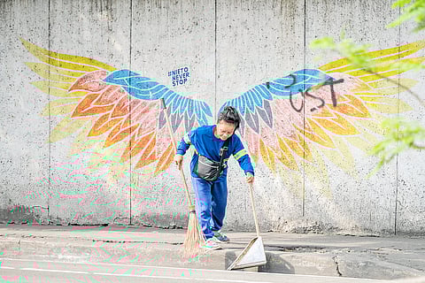(FILE PHOTO) Earth angel Marivel Requintosa, 57, a five-year Job Order employee of the Manila Department of Public Services, cleans the streets of Manila for P8,900 per month. Though she does not get a 13th month salary as a JO, as ruled by Presidential Decree 851 in 1976, this mother of three will keep working in this job — even use her own cleaning materials because the city government does not provide them — to send her kids through senior high and college. She hopes that someday she would be able to experience the privileges the plantilla workers enjoy. Here, she is spotted along Legarda Street in Manila on 6 December. (PHOTOGRAPH BY KING RODRIGUEZ FOR THE DAILY TRIBUNE)