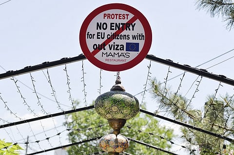 FILE PHOTO: This photograph taken on 28 June 2022, shows a sign reading "No Entry for EU citizens without Visa" displayed at a restaurant in Pristina. (Photo by Kushtrim Ternava / AFP)
