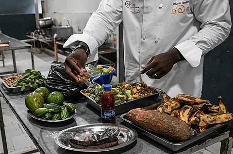 FILE PHOTO: Ivorian chef Charlie Koffi prepares gouagouassou sauce accompanied by rice in his restaurant at Villa Alfira in Abidjan on 4 December 2023. (Photo by Sia KAMBOU / AFP)