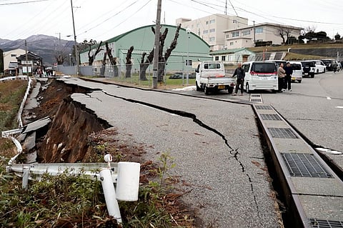 People stand next to large cracks in the pavement after evacuating into a street in the city of Wajima, Ishikawa prefecture on 1 January 2024, after a major 7.5 magnitude earthquake struck the Noto region in Ishikawa prefecture in the afternoon. (Photo by Yusuke FUKUHARA / Yomiuri Shimbun / AFP)
