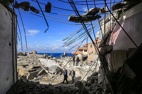 People walk through the rubble of destroyed buildings following strikes on the the town of Naqura in southern Lebanon close to the border with northern Israel on January 4, 2024. Four Hezbollah fighters were killed overnight in southern Lebanon, the Iran-backed movement announced on January 4, in what Lebanese state media said were Israeli strikes on the border town of Naqura. (Photo by AFP)