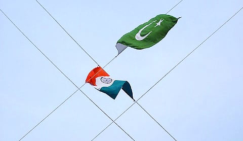 The national flags of India and Pakistan flying against a blue sky, attached to kite strings