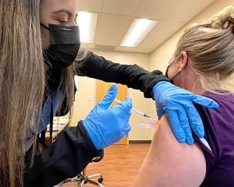 US hits 70% vaccination rate a month late, amid a surge