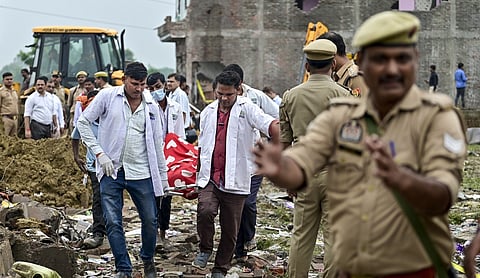 Personnel carry mortal remains after a massive explosion at a firecracker factory, in Kaushambi, Uttar Pradesh. (PTI Photo)