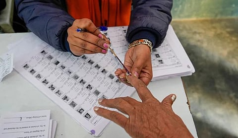 Representational image: An election official applies indelible ink to a voter's finger over electoral roll documents at a polling station. (PTI Photo)