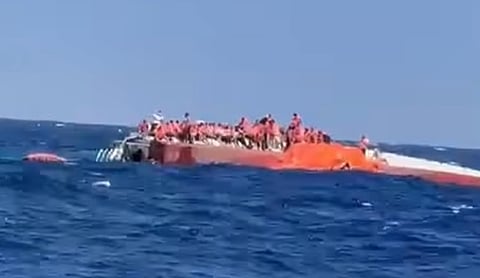 Representational image: People in life jackets await rescue on the hull of a capsized vessel.