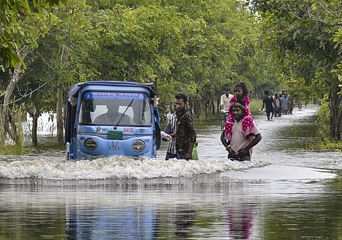 People wade through a flooded road following a rise in the water level of the Punpun river in Patna, PATNA on Sunday, September 6. (PTI Photo)