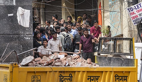 People gather near debris after a building collapse in Satya Niketan, New Delhi, NEW DELHI on Monday, September 7. (PTI Photo)