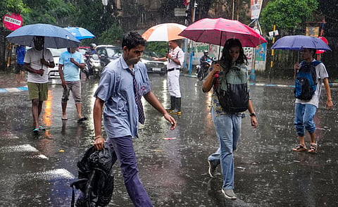 Commuters make their way through Kolkata amid heavy rain on Wednesday. PTI image