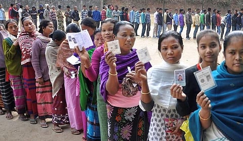 File photo: A queue of voters holds up identification documents.