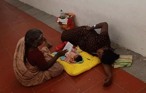 படுக்கை வசதி இல்லாததால் பச்சிளங்குழந்தையுடன் தரையில் படுத்த பெண்