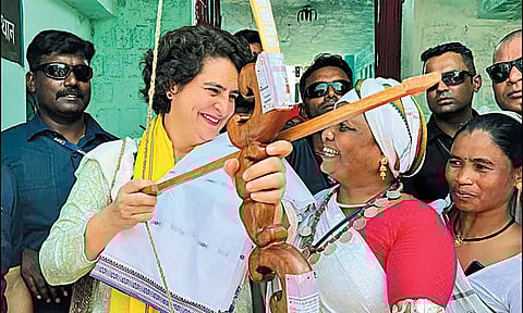 காங்கிரஸ் பொதுக்கூட்டத்தில் பங்கேற்ற பிரியங்கா காந்தி, பழங்குடியின பெண் வழங்கிய வில்லில் அம்பை பொருத்தி பார்த்தபோது எடுத்த படம்.