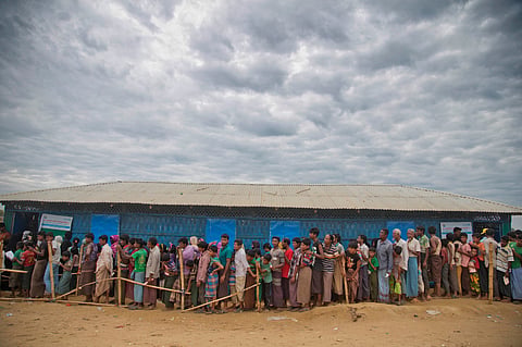 Rohingya Muslims, who crossed over from Myanmar into Bangladesh, wait in queues to receive aid at Kutupalong refugee camp in Ukhiya