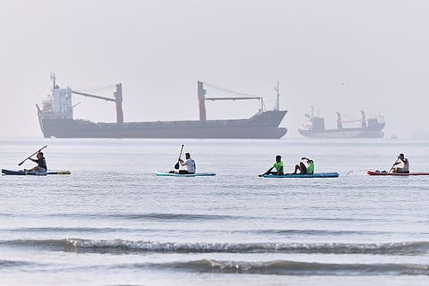 Cargo and service vessels line the horizon as people ride a motorcycle along the Strait of Hormuz, off Bandar Abbas, Iran, Sunday, May 31, 2026