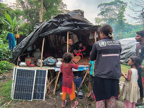 WHO SIMO is conducting a household-level assessment at a bamboo shelter, reviewing health status and vaccination history with the family. Kotalipara Upazila, Gopalganj, 28 April 2026.