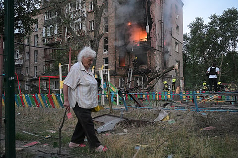 A woman walks past a burning apartment building after a Russian missile attack in Kyiv, Ukraine, 2 July 2026.