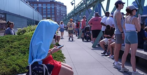 A person shields themselves from the sun at Pier 57 during a heat wave ahead of the International Parade of Sail, Saturday, July 4, 2026, in New York