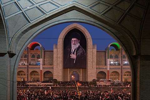 Mourners gather beneath a portrait of the late Iranian Supreme Leader Ayatollah Ali Khamenei during the funeral ceremonies for Khamenei and members of his family at the Imam Khomeini Mosalla Grand Mosque in Tehran, 4 July 2026.