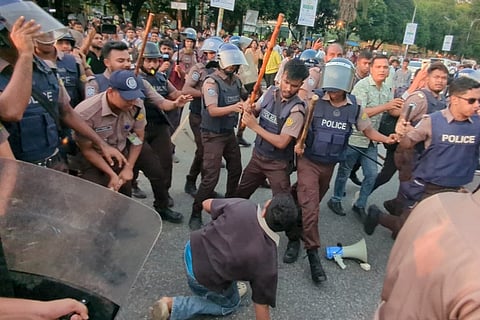 Police wielding sticks surround a protester near the Jatiya Sangsad Bhaban in the capital on July 14, 2026.