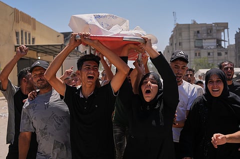 Warda Abu Shaar, center right, carries the body of her 10-year-old son, Motaz Abu Shaar, who was killed by Israeli fire, during his funeral outside Nasser Hospital in Khan Younis, southern Gaza Strip, 14 July 2026.