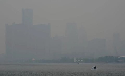 A watercraft sits on the Detroit River amid poor quality due to smoke from fires in Canada, which render skyscrapers barely visible.