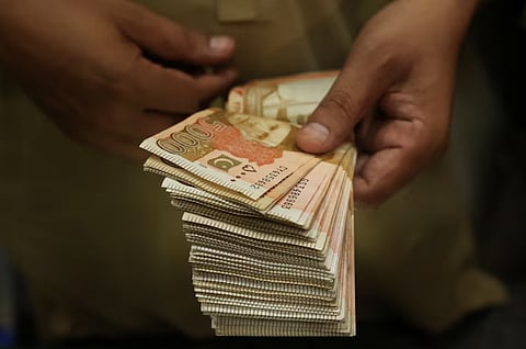 A trader counts Pakistani rupee notes at a currency exchange booth in Peshawar, Pakistan, July 29,2025.