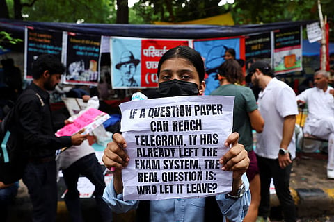 A supporter of India's Cockroach Janata Party (CJP) holds a sign during the ongoing protests, a few days after thousands of protesters marched towards parliament demanding the resignation of Education Minister Dharmendra Pradhan over National Eligibility cum Entrance Test (NEET) examination paper leaks, at Jantar Mantar in New Delhi, India, July 23, 2026.