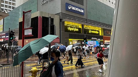 Passersby walk in Hong Kong's Mong Kok district under heavy rain and wind ahead of Typhoon Noul on Saturday, July 25, 2026.