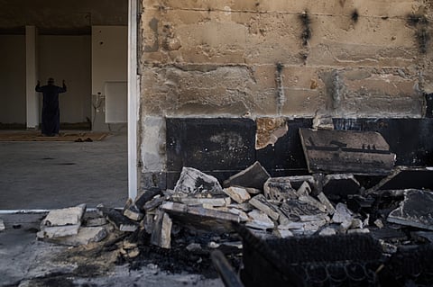 A Palestinian man prays inside a mosque that was burned during an attack by Israeli settlers early in the morning in the West Bank village of Qusra, Sunday, July 26, 2026.
