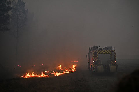 A fire engine drives through smoke of a wildfire raging near Marcheprime, outside, Bordeaux, France, Sunday, July 26, 2026.