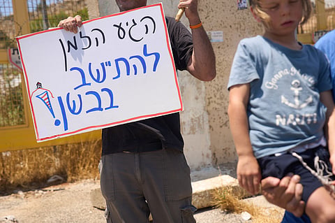 A right-wing Israeli activist holds a sign which reads "Its about time to settle in the Bashan", in the Israeli-occupied Golan Heights, Tuesday, July 21, 2026.