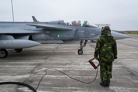 A member of the ground crew of the Swedish Air Force stands next to a JAS 39 Gripen fighter aircraft in Kallinge, Sweden, December 16, 2025.