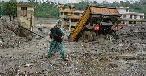 A woman walks through mud and debris left behind by flash flooding in Nepal's Nuwakot district, Saturday, Aug. 29, 2026.