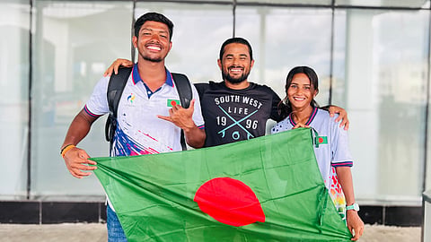 Bangladesh's Asian Games 2026-bound surfers Mohammad Mannan (L), Fatema Akter (R) pose for a photo with their coach Rashed Alam at the Cox's bazar International Airport on Monday.