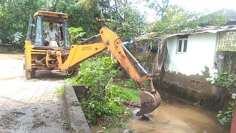 वाडे तळ्यातील पाणी समुद्रात जाणार्यां नाल्यातील गाळ जेसीबीद्वारे काढताना.