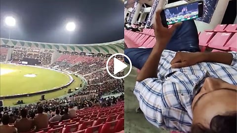 A man watching an IPL match on a mobile phone in Stadium