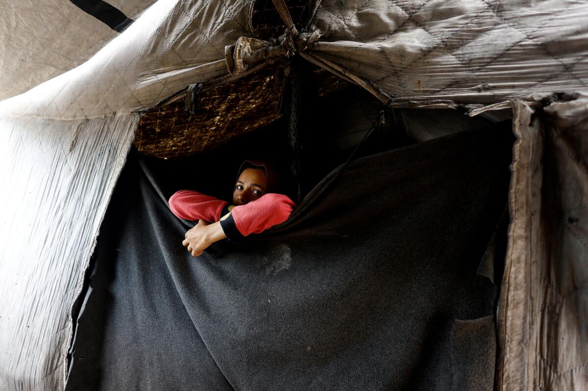 A displaced Palestinian looks out from a tent, in the central Gaza Strip.