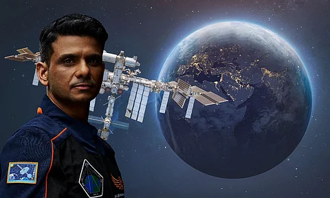 Group Captain Shubhanshu Shukla, wearing a space mission suit, stands confidently with the International Space Station and a partially lit Earth in the background. The image symbolises India's space aspirations and international collaborations in space exploration.